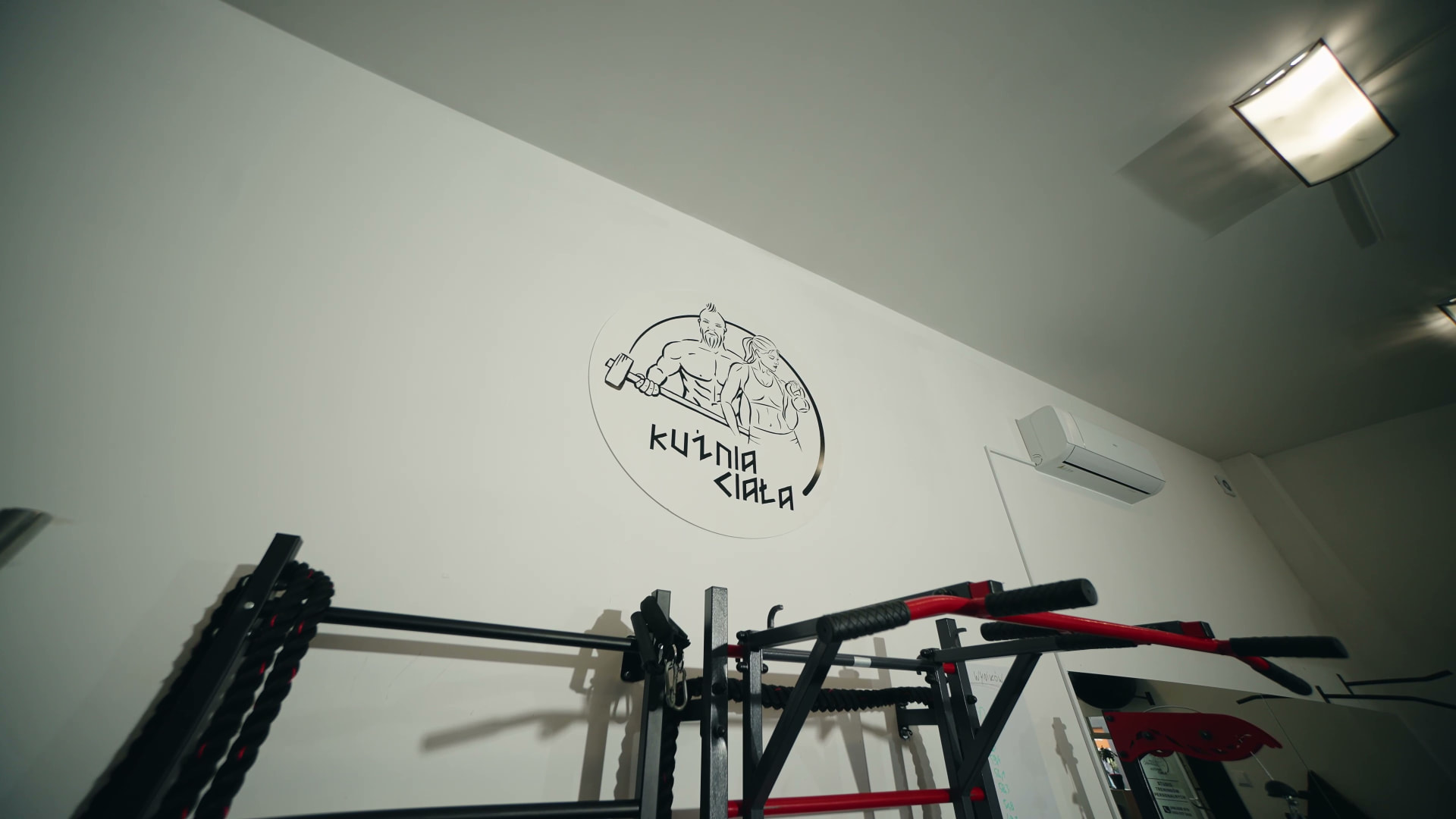 Logo Kuźni Ciała nad stanowiskiem treningowym